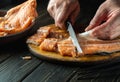 Cutting red fish with a knife on a kitchen cutting board before cooking. Close-up of hands of a chef while cleaning raw fish Royalty Free Stock Photo