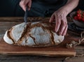 Cutting rustic loaf of sourdough bread by womans hand with a bread knife Royalty Free Stock Photo