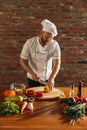 Young Caucasian red-bearded man, chef cooking fresh vegetable salad in cafe, restaurant kitchen. Concept of a correct Royalty Free Stock Photo