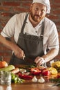 Young Caucasian red-bearded man, chef cooking fresh vegetable salad in cafe, restaurant kitchen. Concept of a correct Royalty Free Stock Photo