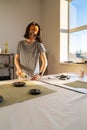 Cutting and sewing in tailor studio: sewer young woman work with fabric in design workshop studio