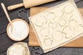 Cutting shaped cookies by mold on paper. Rolling pin. Flour and dough on table
