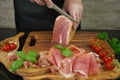 Male hands cutting with sharp knife traditional Spanish dry smoked ham leg