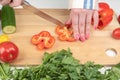 Cutting sweet peppers into small pieces on a wooden cutting board. Royalty Free Stock Photo