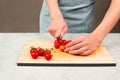 Cutting tomato on a wooden board, prepare salad, healthy food with vegetables, fresh organic nutrition, cooking ingredients Royalty Free Stock Photo