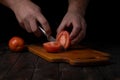 Cutting vegetables. Male hands cutting tomatoes on a cutting board.