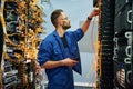 Cutting the wire. Young man is working with internet equipment in server room Royalty Free Stock Photo