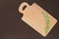 Cutting wooden board with a sprig of rosemary on a dark background Royalty Free Stock Photo