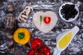 Cutting wooden board with traditional pizza ingridients on dark background, top view