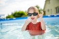 Cuty funny toddler boy having fun in outdoor pool. Child learning to swim. Kid having fun with water toys. Summer activities for Royalty Free Stock Photo