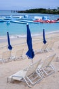 Cyan sea waves hitting sandy beach with dark blue closed umbrellas and sunbeds on aqua park