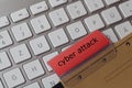 Cyber attack as a term on a red tab of a brown hanging file on a computer keyboard
