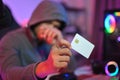 Cyber crime and network security concept. Mystery hacker in hoodie holding credit card in his hand. Royalty Free Stock Photo