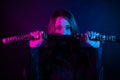 Cyber girl in a black leather jacket at dusk holds a katana. A woman in a club with a colored pink-blue light holds an Asian sword Royalty Free Stock Photo