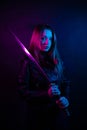 Cyber girl in a black leather jacket at dusk holds a katana. A woman in a club with a colored pink-blue light holds an Asian sword Royalty Free Stock Photo