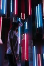 Cyber industry. Simulation of the real world. A woman wears a virtual reality helmet in a neon room. Vertical shot