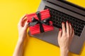 Cyber monday concept. First person top view photo of female hands typing on laptop keyboard and holding red giftbox with ribbon Royalty Free Stock Photo