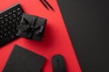 Cyber monday concept. Top view photo of black giftbox with ribbon bow computer mouse keyboard notepad and pencils on bicolor red Royalty Free Stock Photo