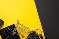 Cyber monday concept. Top view photo of keyboard computer mouse shopping cart and alarm clock on bicolor yellow and black Royalty Free Stock Photo