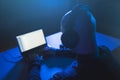 Hacker with headset typing on laptop in dark room