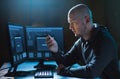 Hacker with smartphone and computers in dark room