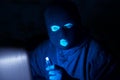 Cybercrime, hacking and technology crime. Masked hacker working in the darkness stealing data and personal identity information