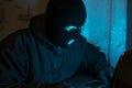 Cybercrime, hacking and technology crime. Masked hacker working in the darkness stealing data and personal identity information