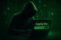 Cybercrime scene with hooded figure transferring data amid binary code and green matrix graphics Royalty Free Stock Photo