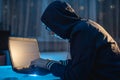 Cybercriminal in the hood typing program code while stealing access databases with passwords. Hackers and cyber security