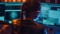 Cyberpunk girl backview types on keyboard multiple monitors with strings of code