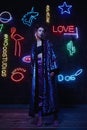 Cyberpunk shooting of model wearing bathrobe with glitter against wall of neon
