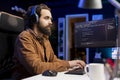 Cybersecurity expert enjoying audiobooks, using PC to patch security exposures Royalty Free Stock Photo