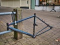 A cycle frame, stripped bare of all fixtures and fittings lies shackled to a cycle lockup Royalty Free Stock Photo