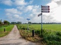 Cycle path and signpost with directions for bicyclists in polder near Langweer, Friesland, Netherlands Royalty Free Stock Photo