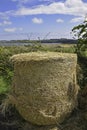 Cyclindrical hay stack with blurred rural background on a sunny day with blue sky and clouds