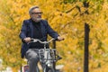 Cycling and active ways to spend time in autumn. Happy gray-haired bearded elegant man riding a city bike in beautiful