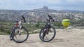 Cycling in Cappadocia With Uchisar Castle and Hot Air Balloon in Background