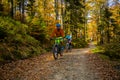 Cycling, mountain biker couple on cycle trail in autumn forest. Mountain biking in autumn landscape forest. Man and woman cycling