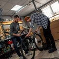 Cycling servicemen assembling new bike in workshop