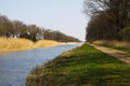 Cycling tour along straight canal with reed and bare trees on the riverbank in spring Royalty Free Stock Photo