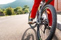 Cycling. A woman in red sportswear is sitting on a Bicycle with her foot on the pedal. Legs are close-up. Copy space. Royalty Free Stock Photo