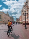 A cyclist with a backpack on his back rides along the Arbat street in Moscow