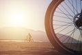 A cyclist behind a big bike wheel on the beach Royalty Free Stock Photo