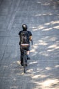 Cyclist in black clothes with a backpack rides a bicycle on a footpath