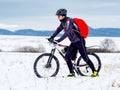 Cyclist in black sport suit pushing the mountain Bike on the Snowy Trail Royalty Free Stock Photo