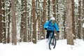 Cyclist in Blue Riding the Mountain Bike in Beautiful Winter Forest. Extreme Sport and Enduro Biking Concept. Royalty Free Stock Photo