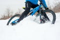 Cyclist in Blue Riding Mountain Bike on Rocky Winter Hill Covered with Snow. Extreme Sport and Enduro Biking Concept.