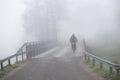 Cyclist on bridge in heavy fog on gloomy autumn day