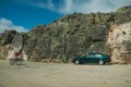 Cyclist and car on roadway in a rocky landscape