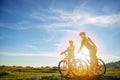 Cyclist couple with mountain bikes standing on the hill under the evening sky and enjoying bright sun at the sunset. Royalty Free Stock Photo